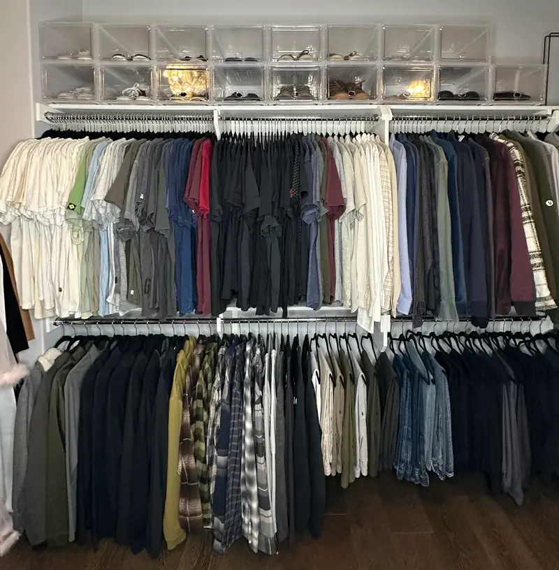 After: men's side of a Huntington Beach walk-in closet with shirts hung by color and shoes in clear boxes above