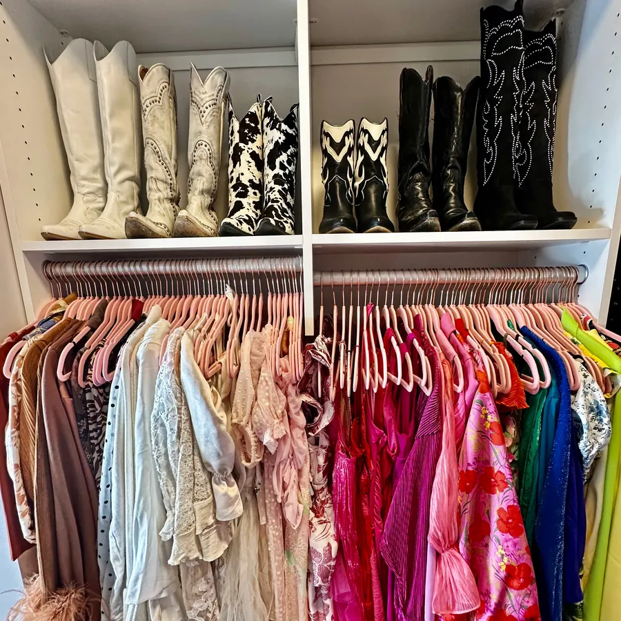 Boot shelf above color-sorted clothes on pink velvet hangers