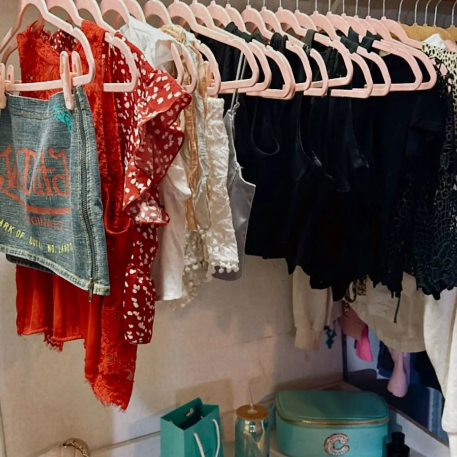 Color-sorted hanging clothes above styled shelves