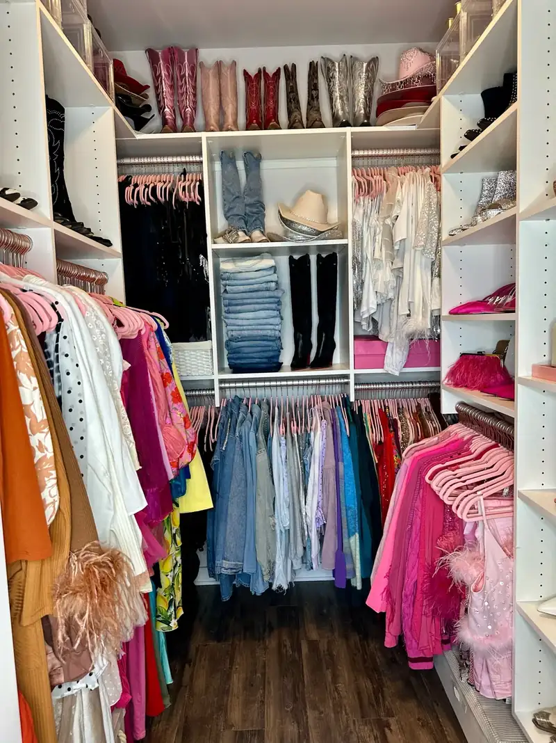 After: Nashville walk-in closet with clothes sorted by color on pink hangers and cowboy boots on the top shelf