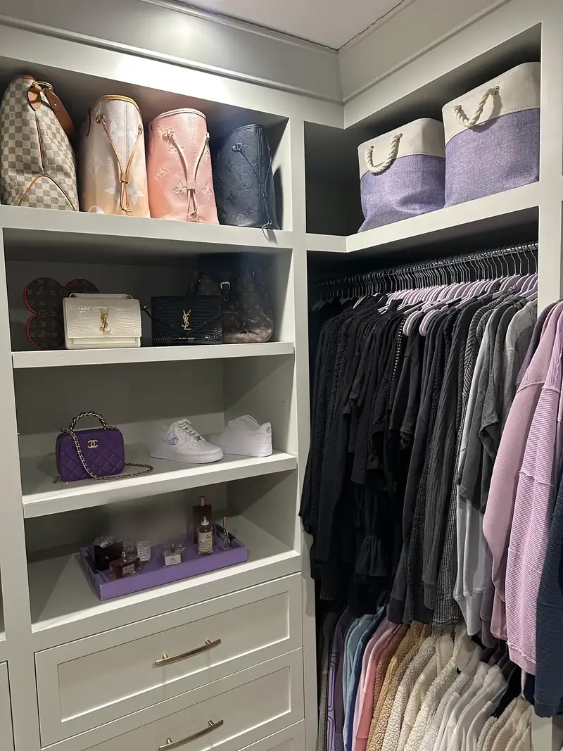 After: women's side of a West Hollywood walk-in closet with handbags on sage shelves, lavender bins and neat rows of tops