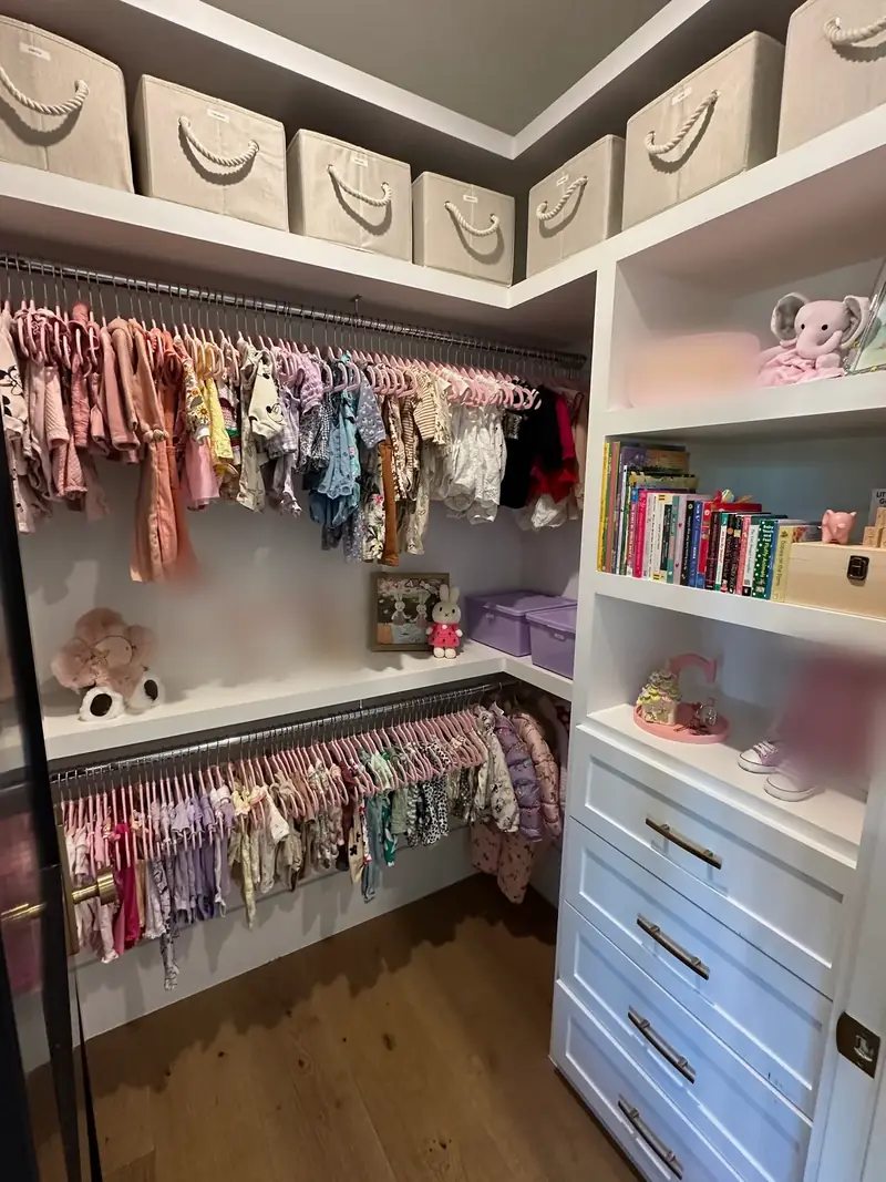 After: West Hollywood kids' walk-in closet with tiny clothes on matching hangers, books on a shelf and closed white drawers