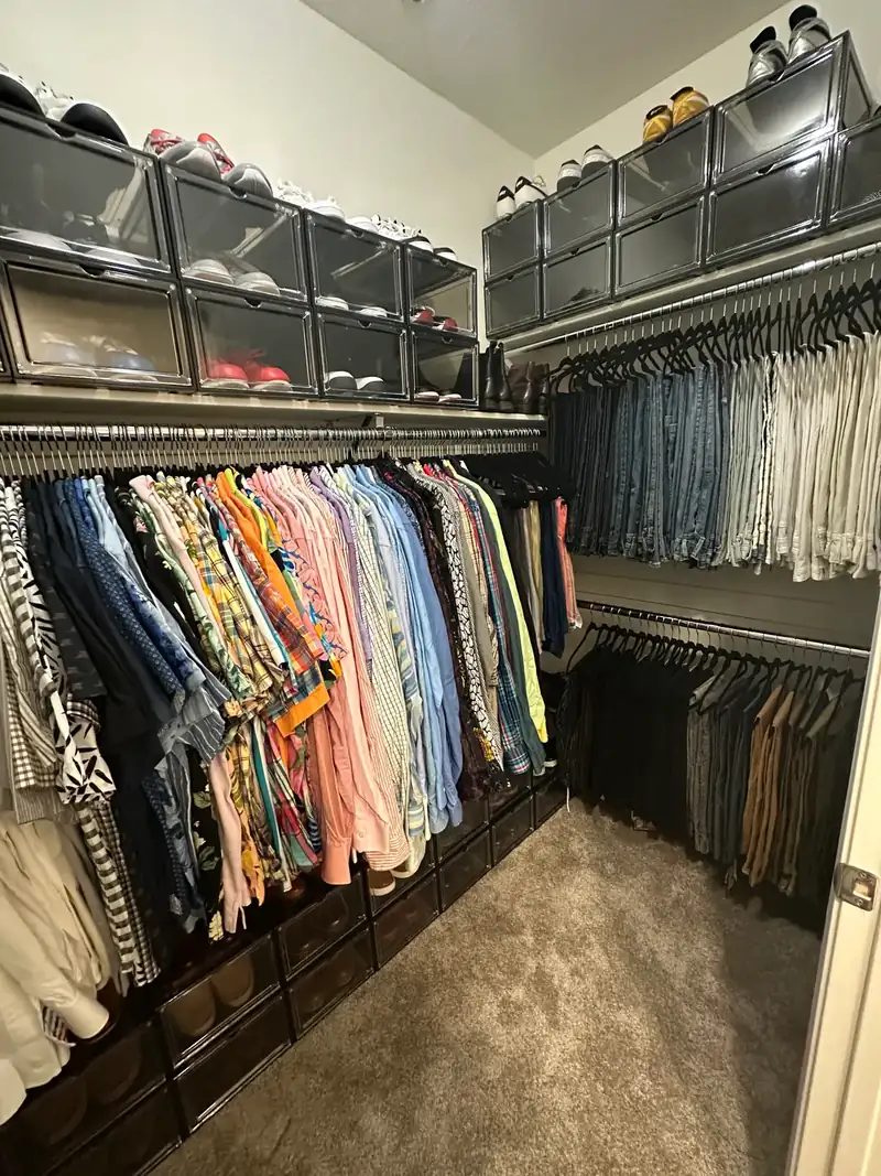 After: West Hollywood men's walk-in closet with shirts hung by color, pants on a second rod and shoes in clear boxes up top