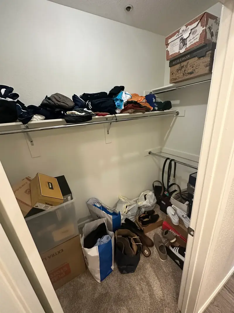 Before: West Hollywood men's walk-in closet with bags, boxes and shoes on the floor and clothes piled on a shelf