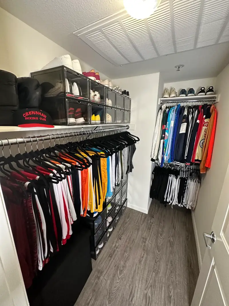 After: West Hollywood men's walk-in closet with jerseys on matching black hangers and sneakers in clear boxes up top