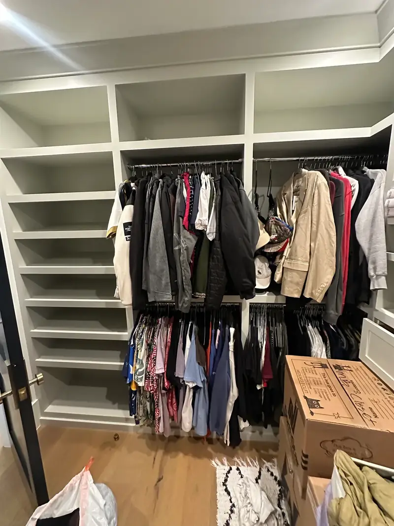 Before: West Hollywood walk-in closet with empty shelves, crowded rods and moving boxes on the floor