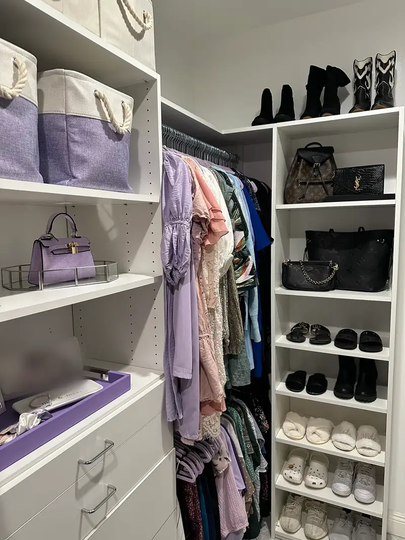 After: West Hollywood walk-in closet with handbags, lavender bins and shoes on white shelves next to hanging dresses